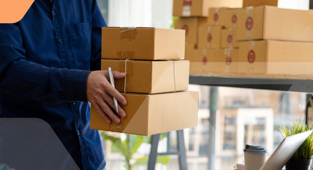 Person holding a stack of three brown cardboard boxes for shipping or returns processing