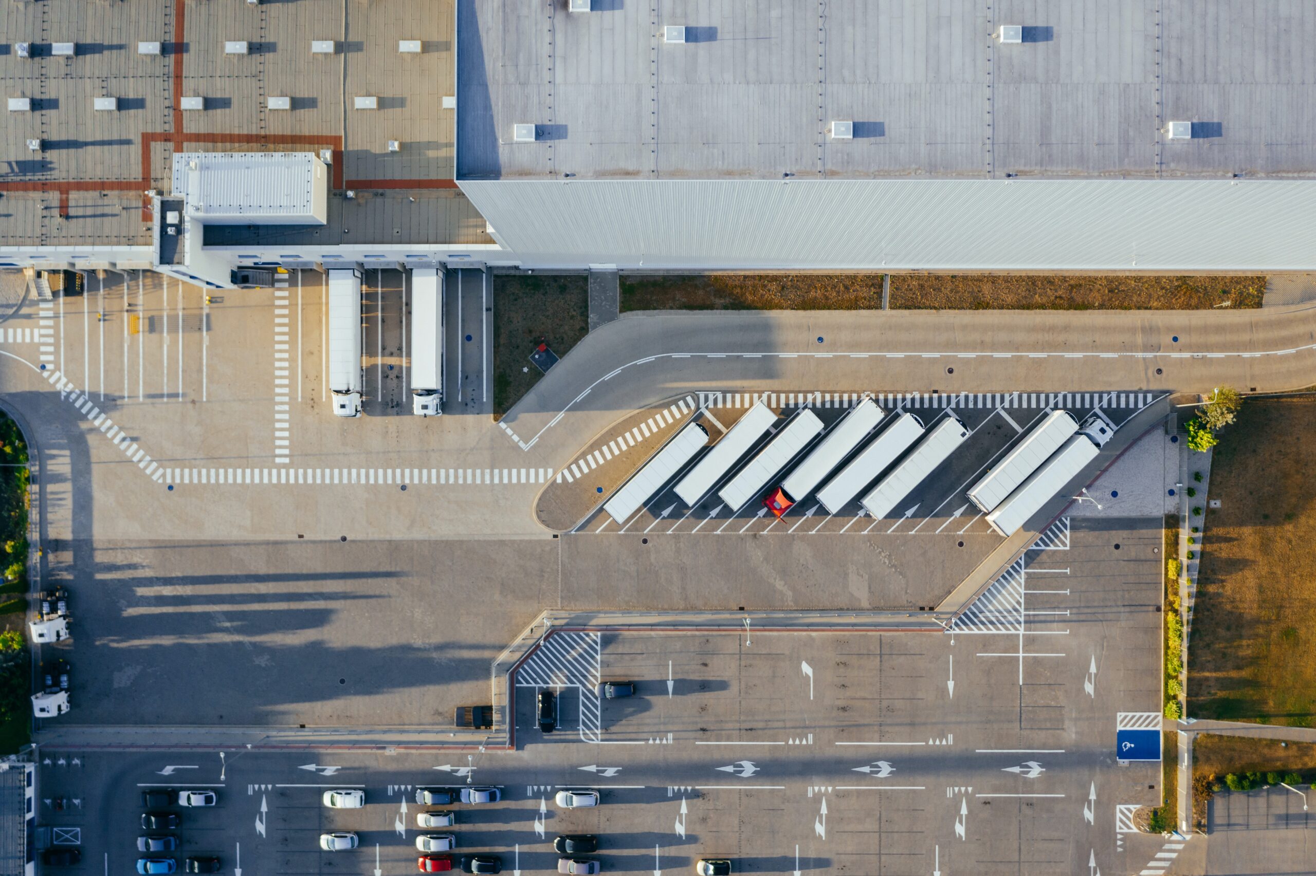 agile supply chain aerial view of a distribution center with trailers and cars parked 