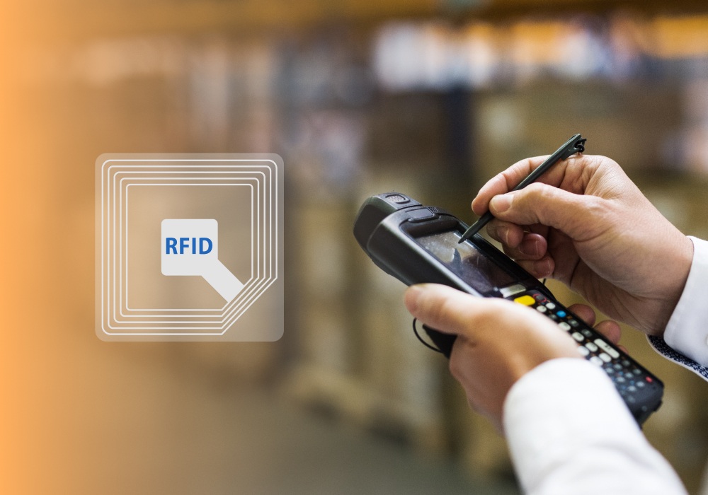 Close-up of hands using a stylus on a handheld RFID scanner in a warehouse, with a digital RFID icon overlay on the left side of the image.